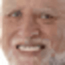 a close up of an elderly man 's face with a beard smiling .