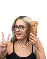 a woman wearing glasses and a necklace is holding a burrito and giving the peace sign