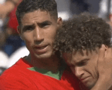 two men with curly hair are hugging each other