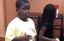 a boy in a yellow shirt is standing next to a girl in a black shirt .