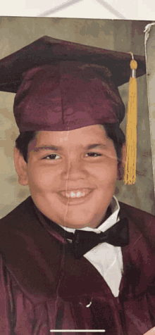 a young boy in a graduation cap and gown smiles for the camera