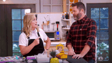 a man and a woman are standing next to each other in a kitchen with a nbc logo on the wall