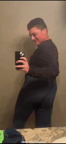 a young man is taking a selfie in a bathroom mirror .