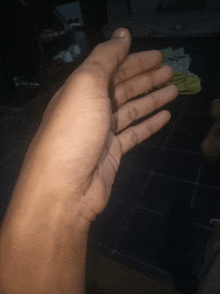 a close up of a person 's hand against a blue tile floor