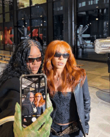 a woman with red hair is taking a picture of herself and another woman