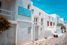 a white building with a blue sign that says " anna mykonos "