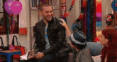 a man in a leather jacket is sitting on a couch talking to a girl .