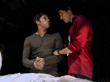 a man in a red shirt holds the arm of another man