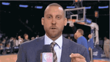 a man in a suit and tie is holding a microphone with nba tv on it