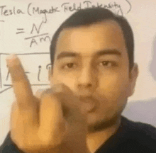 a man is pointing at the camera with his middle finger in front of a white board .