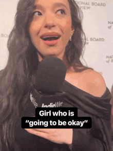 a woman talking into a microphone with the words girl who is going to be okay on the bottom