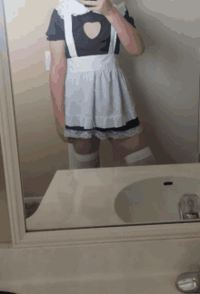 a person in a maid costume is taking a selfie in front of a mirror