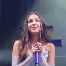 a woman in a blue dress is singing into a microphone on stage .