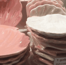 a stack of pink and white plates with a sign that says 1 gab dekoratif