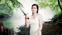 a woman in a white tank top holding a sword