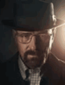 a man with a beard and glasses is wearing a hat and tie .