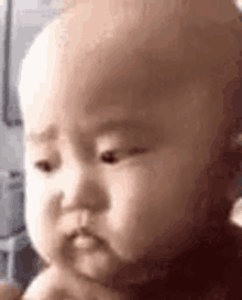 a close up of a baby making a funny face with his hand in his mouth .