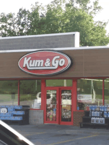 a kum & go store with a red door and a red sign