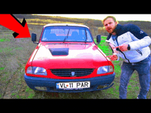 a man standing in front of a red car with a license plate that says vl11 par