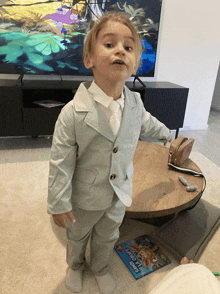 a little boy in a suit is standing next to a book that says " snoopy leaves "