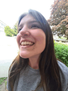 a woman in a grey shirt smiles with her mouth open