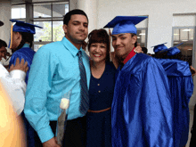 a man in a blue shirt stands next to a woman and a boy in a blue cap and gown