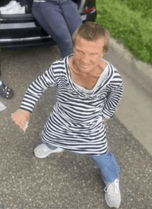 a man wearing a striped shirt is standing on the street