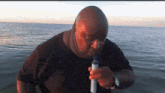 a man in a black shirt is smoking a cigarette in the water