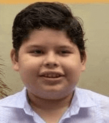 a young boy wearing a white shirt and smiling for the camera .