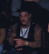 a man wearing a black jacket and a necklace with a cross on it