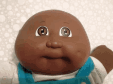 a cabbage patch doll with big eyes and a blue bib