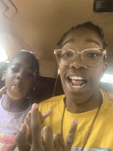 a little girl sticking her tongue out next to a man wearing glasses and a yellow shirt