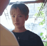 a young man wearing a black shirt and a necklace with a dolphin pendant