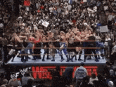 a group of wrestlers are fighting in a wrestling ring with a crowd watching ..