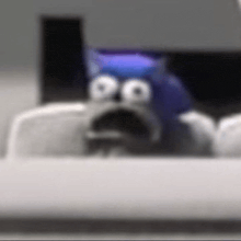 a cartoon character with a surprised look on his face is sitting on a desk .