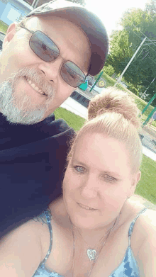 a man and a woman are posing for a selfie at a park .