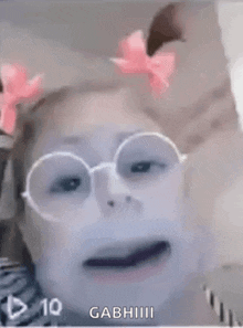 a girl wearing glasses and a pink bow on her hair is making a funny face .