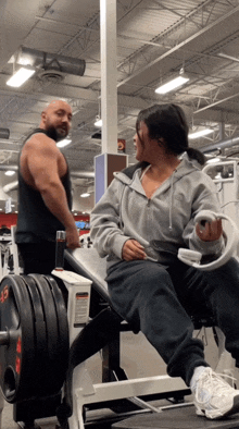 a man stands next to a woman sitting on a machine that says 35 on it