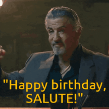 a man in a suit holds a glass of whiskey and says " happy birthday salute ! "