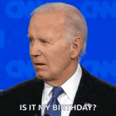 a man in a suit and tie is talking into a microphone and saying `` is it my birthday ? ''