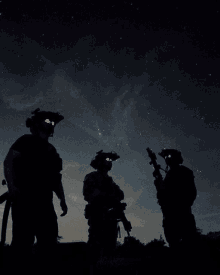 three soldiers are silhouetted against a night sky with stars