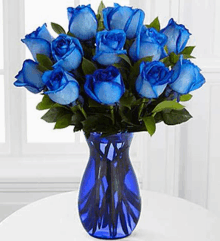 a vase filled with blue roses is on a table .