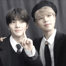 two young men are posing for a picture and one is wearing a louis vuitton brooch