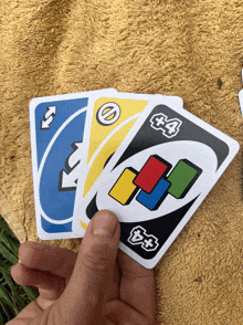 a hand is holding four uno playing cards in a stack