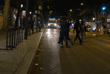 a group of people walking down a street with an ambulance behind them