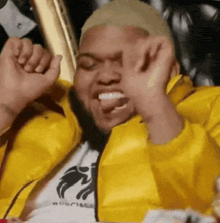 a man in a yellow jacket is making a funny face with his mouth open