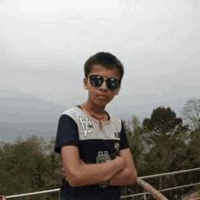 a young boy wearing sunglasses and a necklace is standing on a balcony .