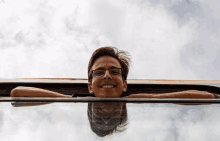 a young man wearing glasses is leaning his head out of a car window