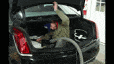 a man using a vacuum in the trunk of a car