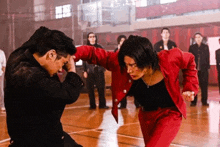 two men in red jackets are fighting on a wooden floor